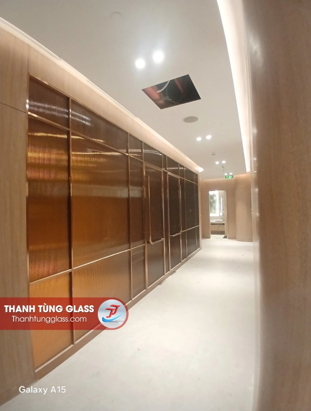 Vách kính sọc trang trí ánh đồng ốp tường hành lang Resort Hoiana, chia ô bằng khung nhôm Slim vàng
